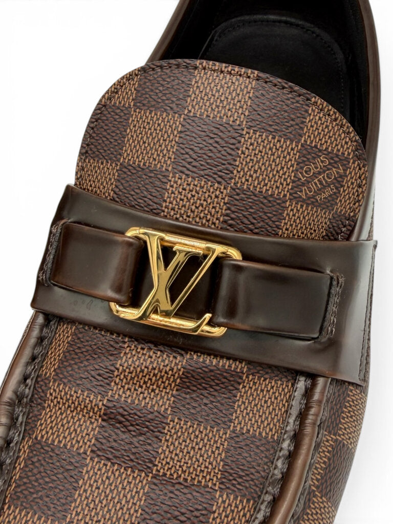 Detailed view of Louis Vuitton men's Damier Ebene loafer with gold LV emblem, polished leather strap and coated canvas. From designer consignment boutique, Dee Black, in Perth, Western Australia.